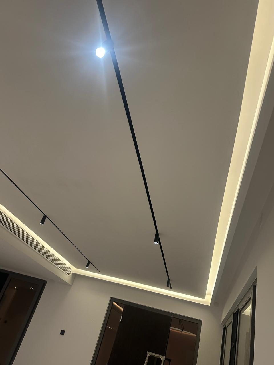 سقف بتجويف مخفي بإضاءة LED دافئة وكشافات سوداء على مسار